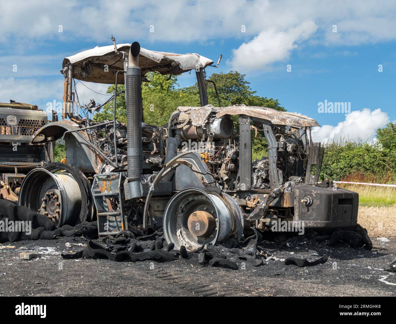 Verbrannte Überreste eines landwirtschaftlichen Traktors auf einem Feld nach einem Brand, der den Traktor und die Ballenpresse völlig zerstörte, Leicestershire, England, Großbritannien Stockfoto