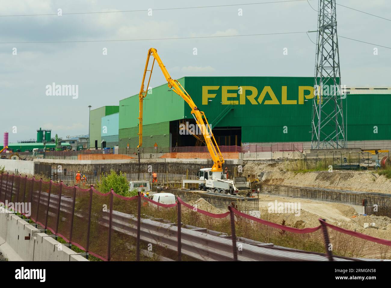 Brescia, Italien - 13. Juni 2023: Produktionsgebäude des Feralpi-Unternehmens, das Stahlerzeugnisse herstellt. Blick auf ein grünes Gebäude mit einem gelben Schild Stockfoto