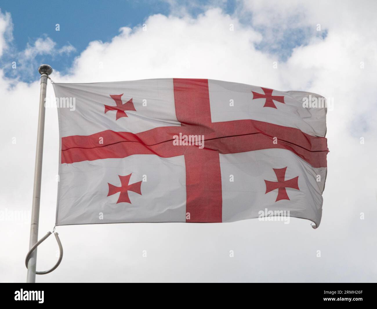 Die Flagge Georgiens, auch bekannt als die Fünffachsflagge, ist eines der nationalen Symbole Georgiens, das im Wind von einem Fahnenmast winkt. Stockfoto
