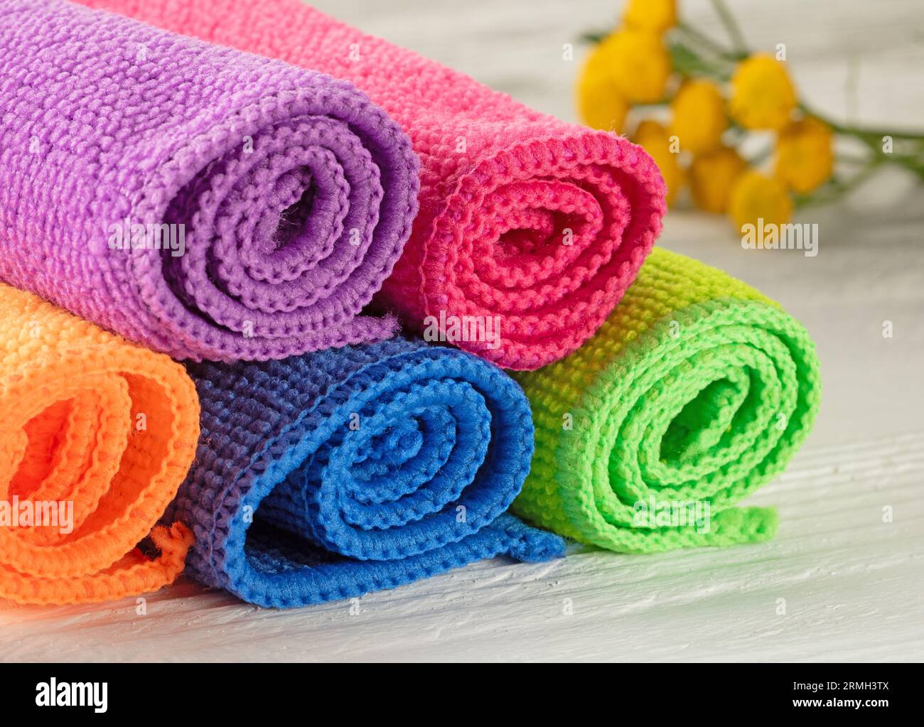 Helle, mehrfarbige Küchenservietten, die in Rollen auf einem Holztisch eingerollt sind. Stockfoto