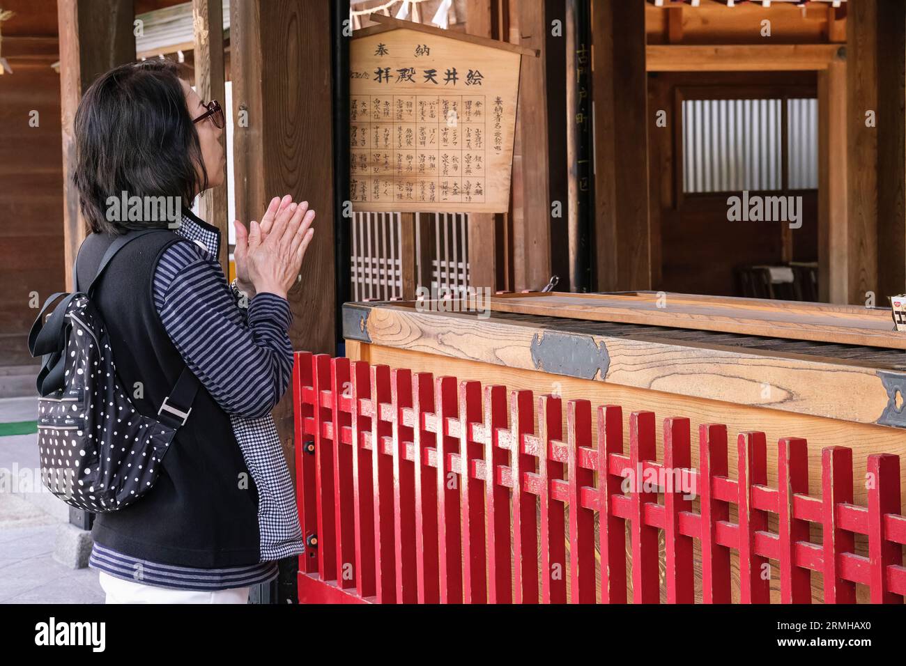 Japan, Kyushu, Fukuoka, Hakata. Kushida Shinto-Schrein. Frau klatscht, um die Aufmerksamkeit der Götter zu erregen. Stockfoto