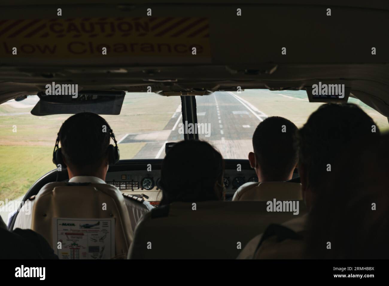 Silhouetten von Passagieren gegen die Start- und Landebahn, die in einem kleinen Flugzeug am Philip S.W. Goldson International Airport in Belize City landen Stockfoto