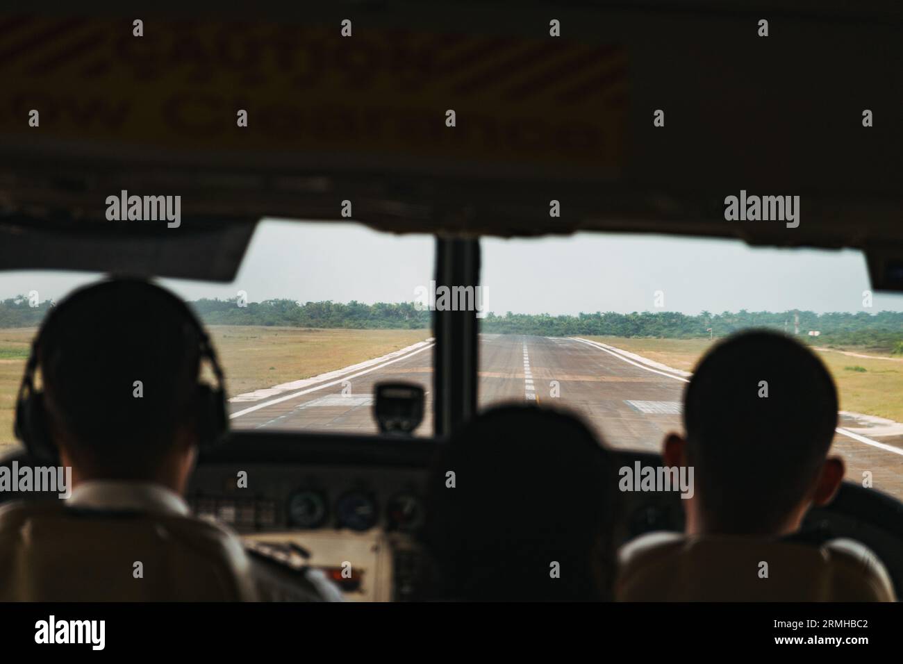 Silhouetten von Passagieren gegen die Start- und Landebahn, die in einem kleinen Flugzeug am Philip S.W. Goldson International Airport in Belize City landen Stockfoto