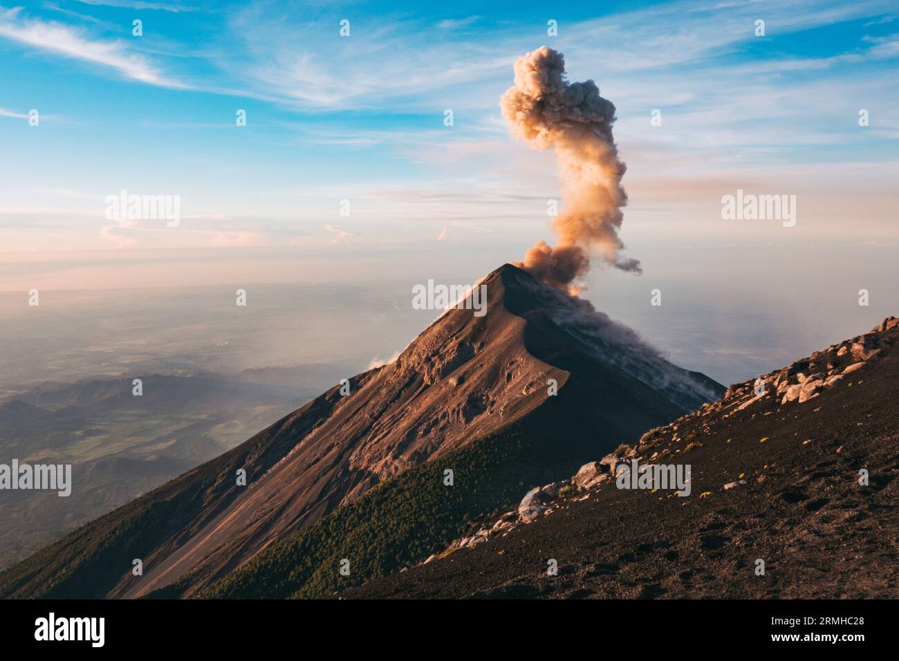 Eine Rauch- und Aschewolke bricht beim Sonnenaufgang aus dem Fuego Vulkankrater aus, wie vom benachbarten Vulkan Acatenango in Guatemala aus gesehen Stockfoto
