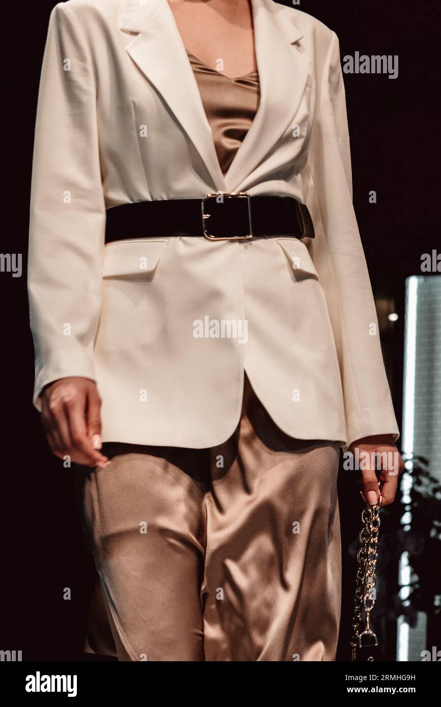 Modische Details aus klassischer weißer Jacke, Seidenrock und Ledergürtel auf einer weiblichen Figur. Designerkollektion Kleidung. Catwalk Fashion Week Stockfoto