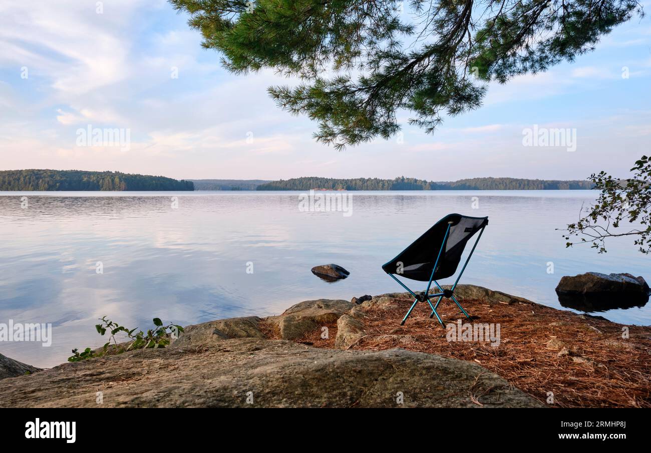 Ein leichter Campingstuhl sitzt auf einer Insel mit Blick auf einen See im Algonquin Park. Stockfoto