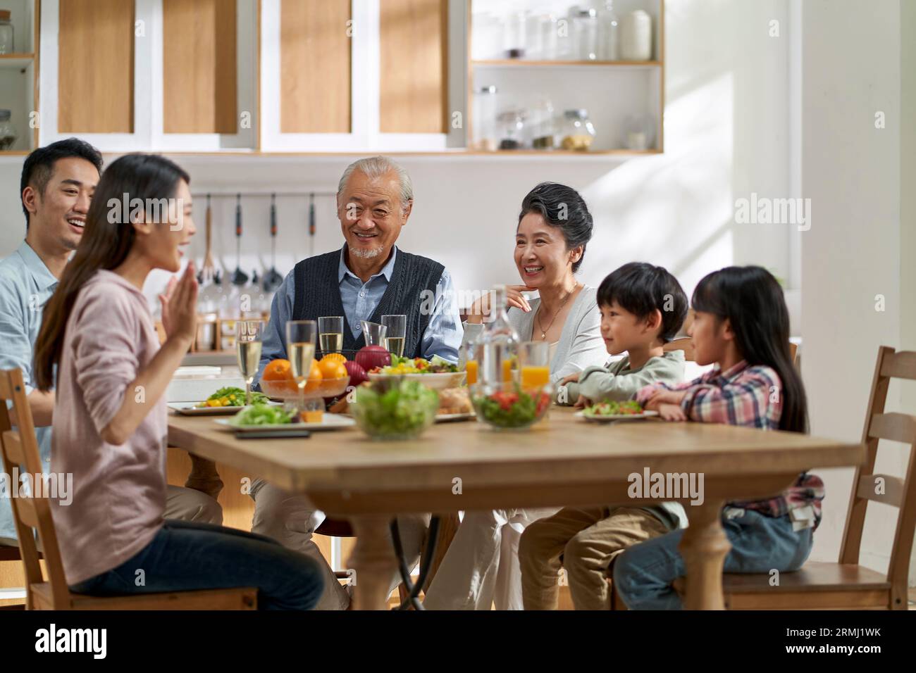 Mehrere Generationen asiatischer Familien unterhalten sich, während sie zu Hause zusammen essen Stockfoto