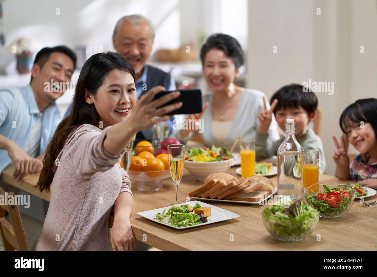Drei Generationen asiatischer Familie nehmen ein Selfie, während sie zusammen essen Stockfoto