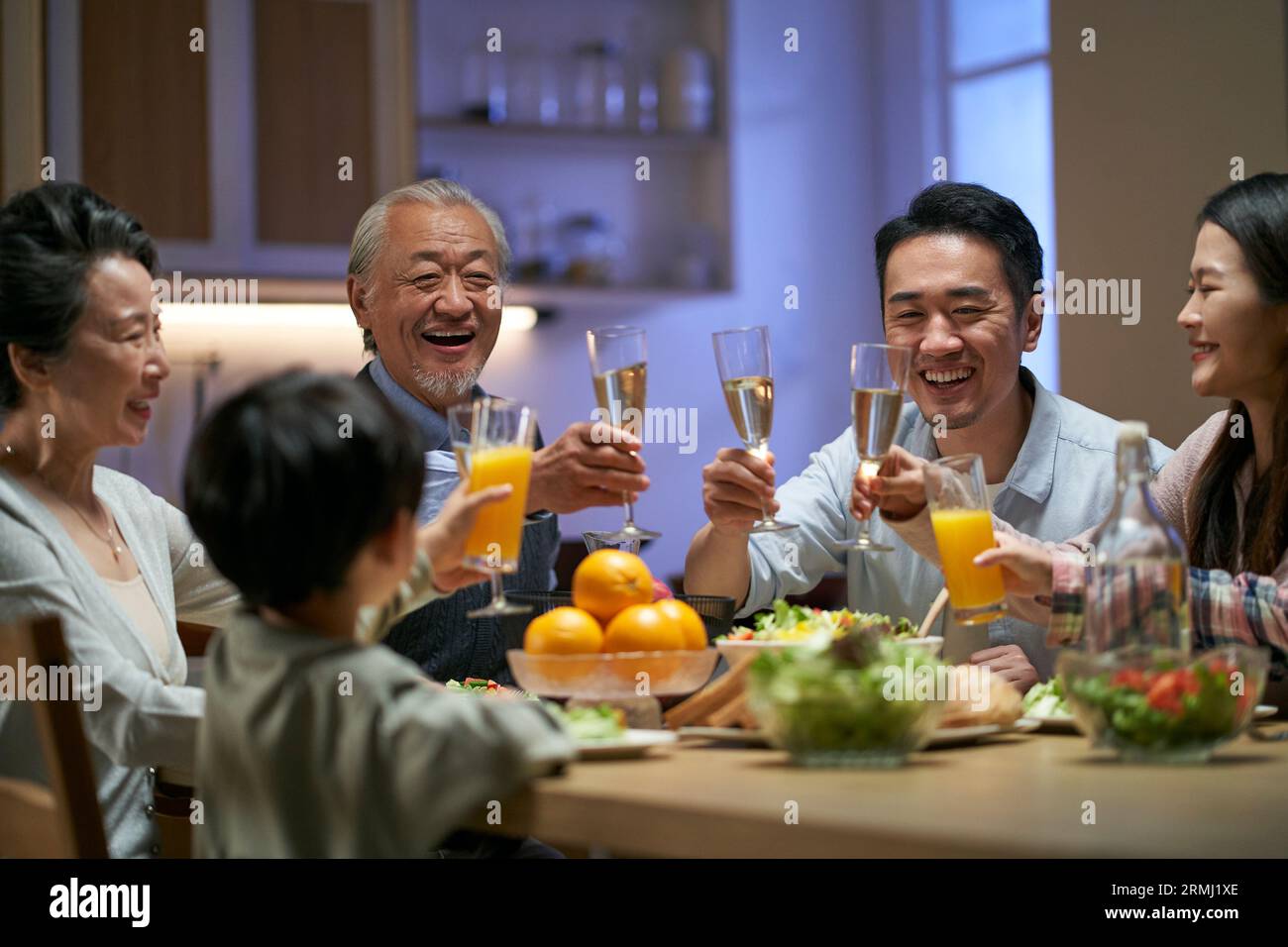 Eine asiatische Familie aus drei Generationen zu Hause, die den Urlaub mit einem Toast feiert Stockfoto