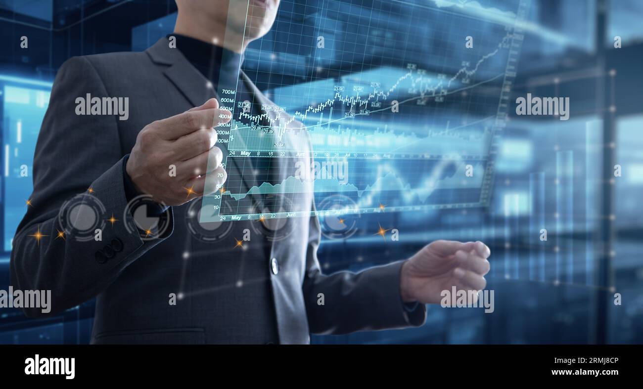Asiatischer Geschäftsmann im Büro, der mit Augmented Reality oder virtuellem Touchscreen interagiert, um Diagramme für die Analyse von Geschäftsdaten zu prüfen Stockfoto