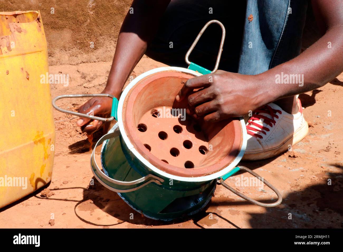 Ein Mann wird gesehen, wie er einen Holzkohleofen herstellt, der lokal als „Mbaula“ bekannt ist, in der Gemeinde Mtandile, Lilongwe. Der Holzkohleofen besteht aus Metall und Ton. Malawi. Stockfoto