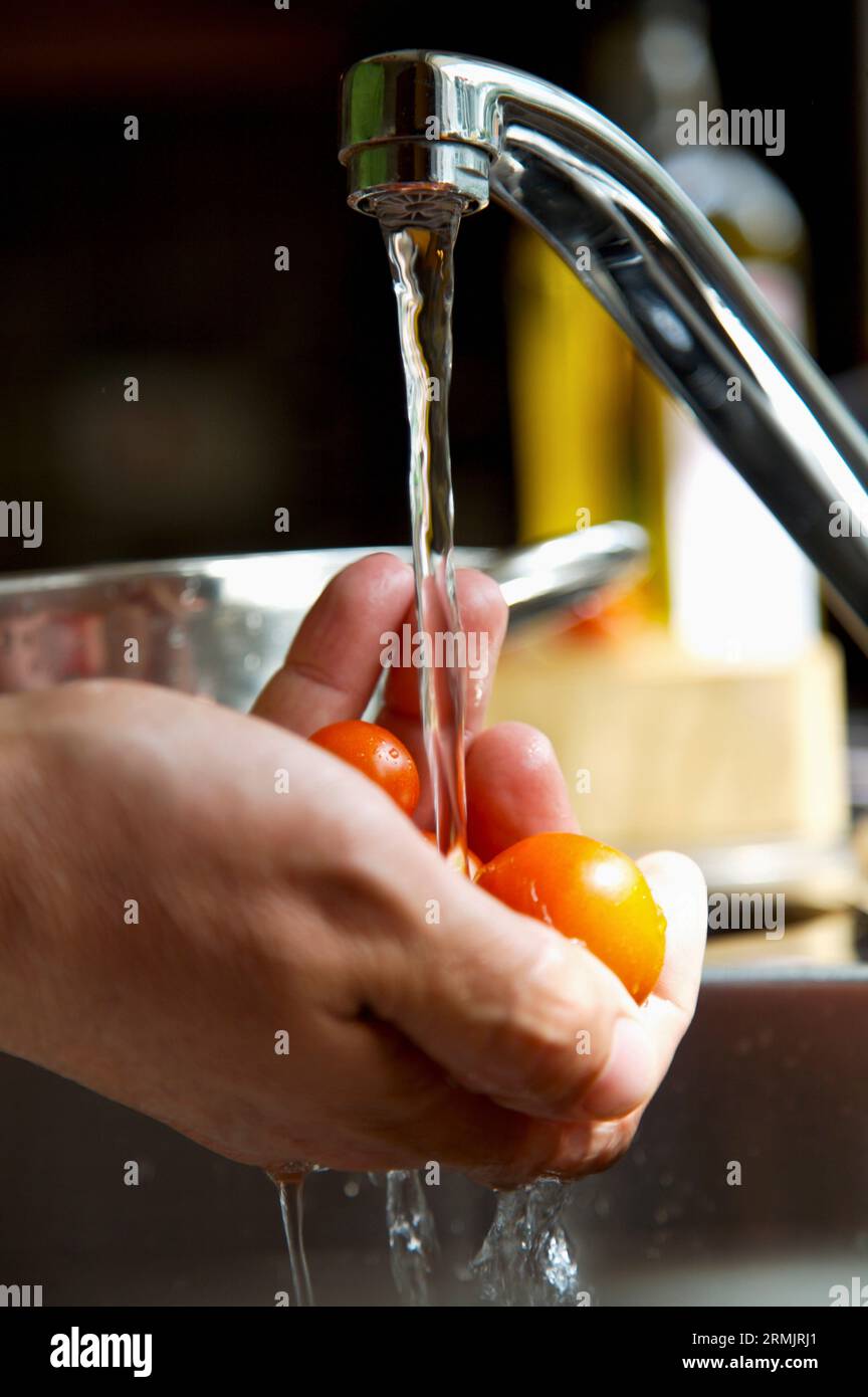 Mannes Hände waschen-Cherry-Tomaten mit fließendem Wasser Stockfoto