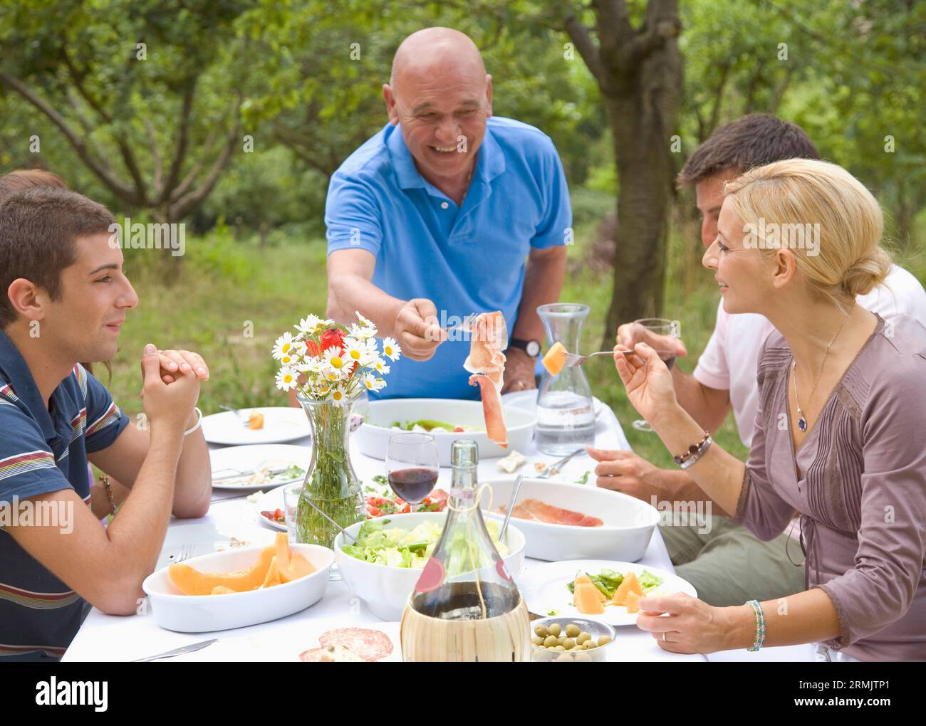 Glatze Opa mit Schinken in Familiengruppe Stockfoto