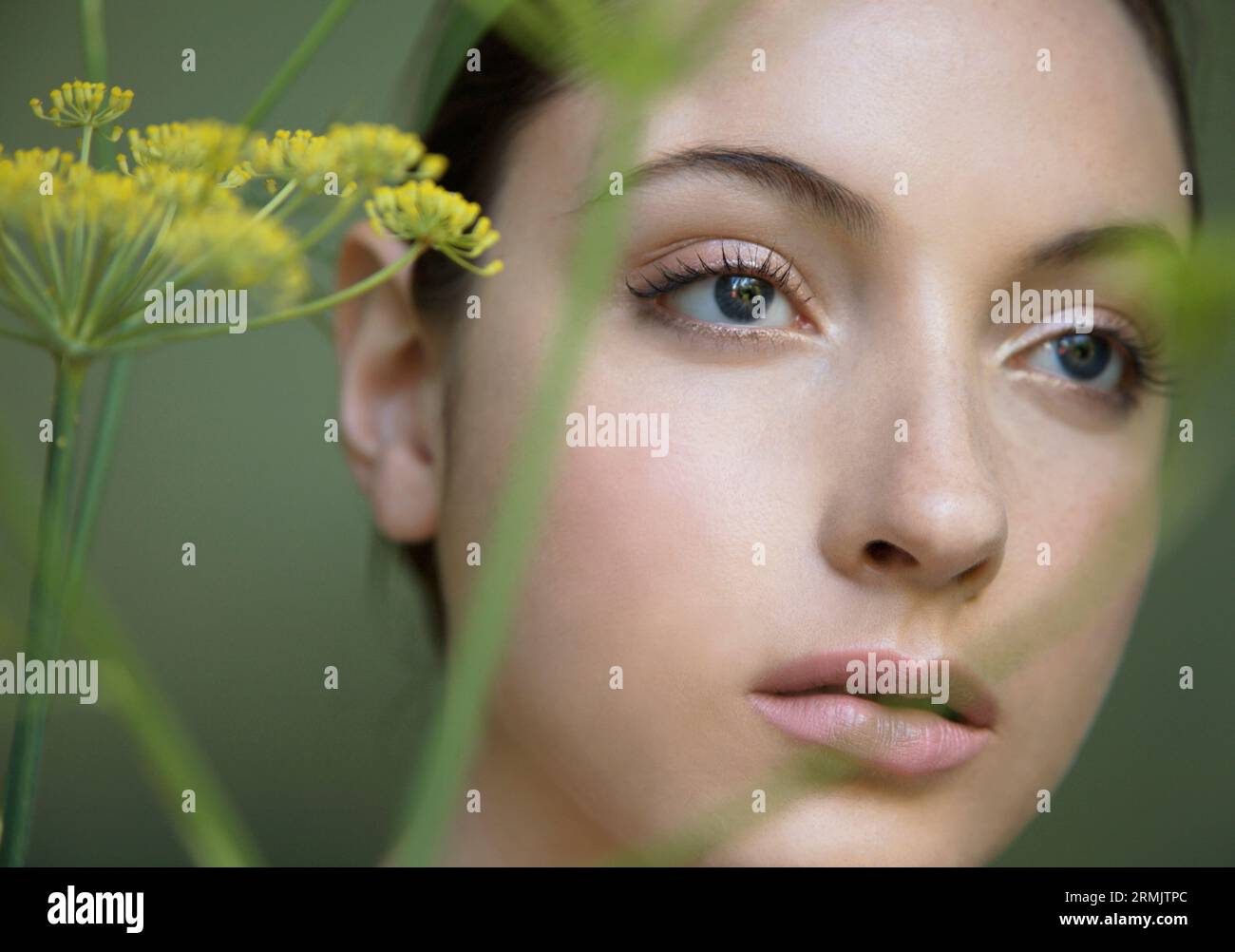 Junge schöne Frau gedankenverloren mit gelber Blume Stockfoto
