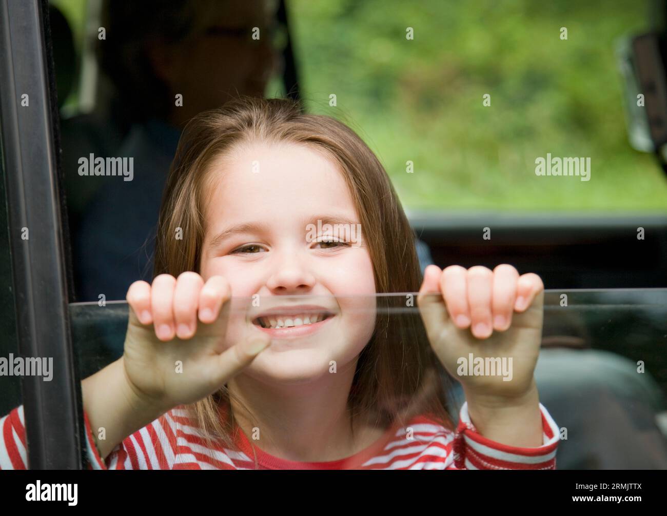 Junges Mädchen lächelnd mit Händen mit Autofenster Stockfoto