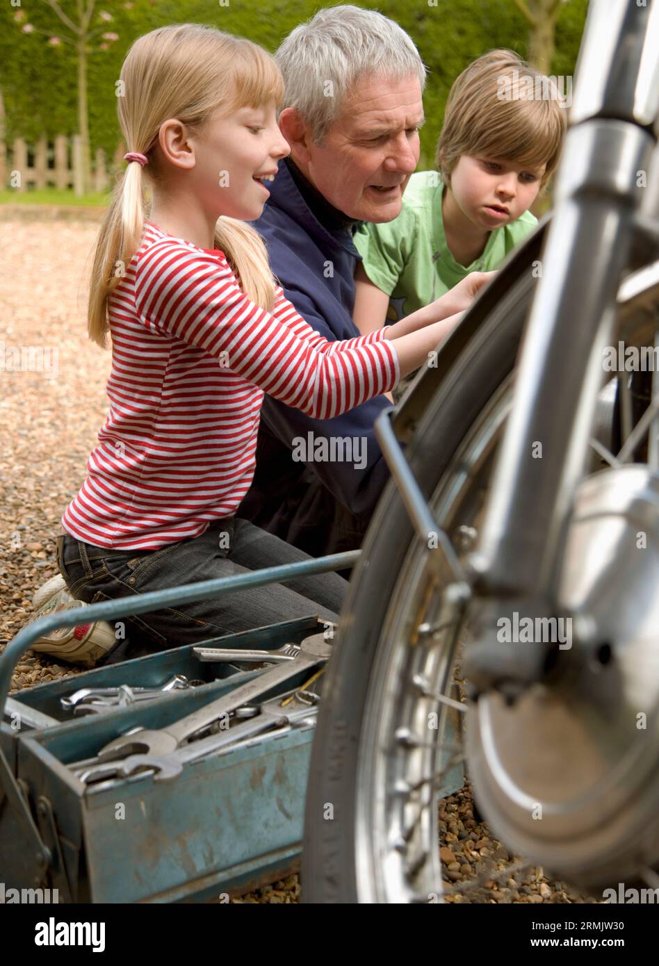 Enkel hilft Großvater Motorrad zu reparieren Stockfoto