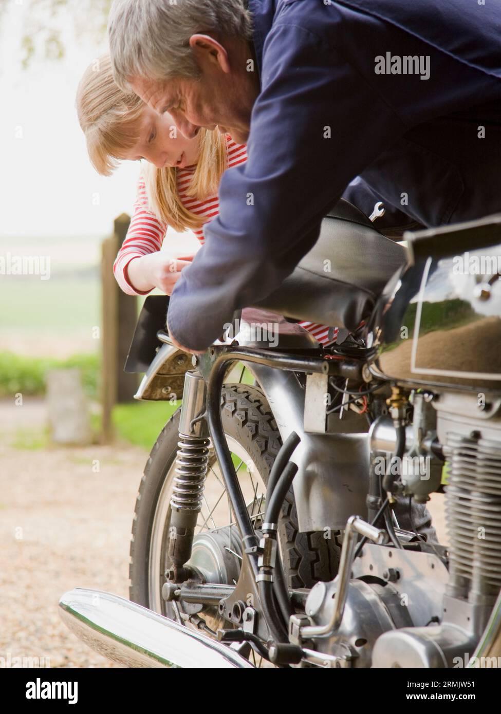 Junges Mädchen hilft Großvater Motorrad zu reparieren Stockfoto
