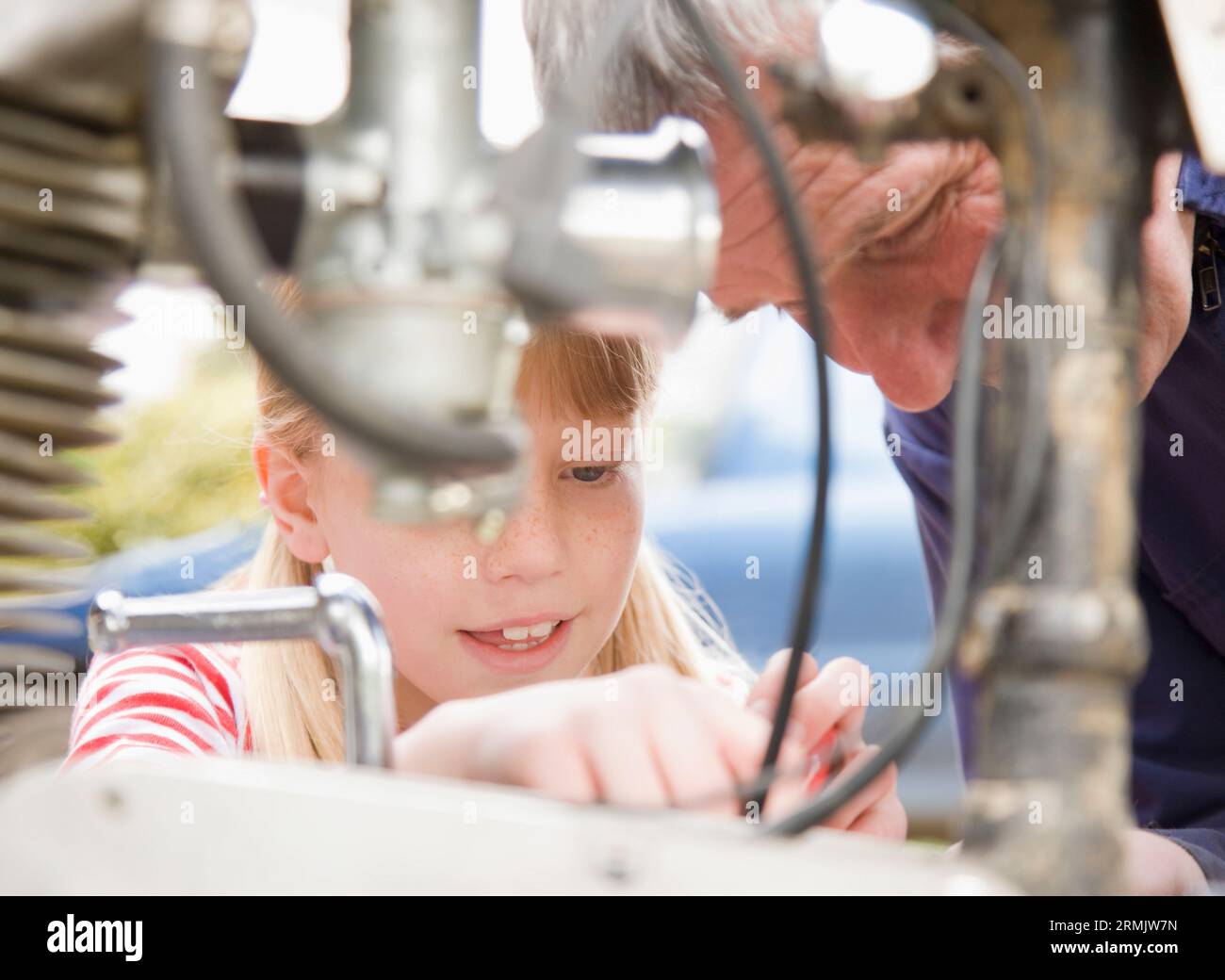 Junges Mädchen hilft Großvater Reparatur Motorrad Motor Stockfoto