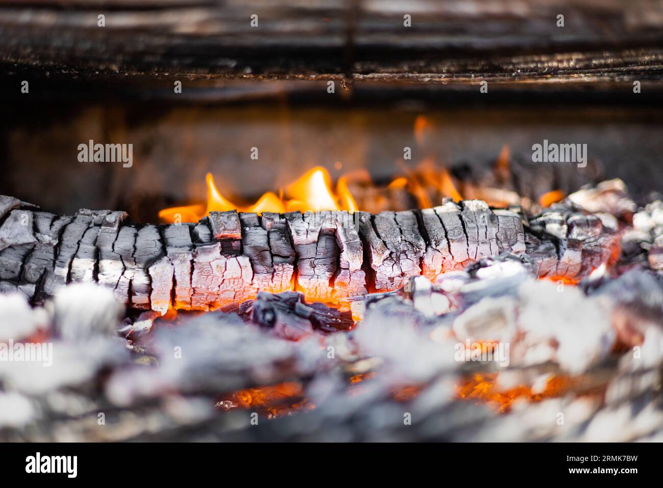 Grillgrube mit heißen Kohlen. Glühende und flammende Holzkohlegriketts für Feuergrill. Stockfoto