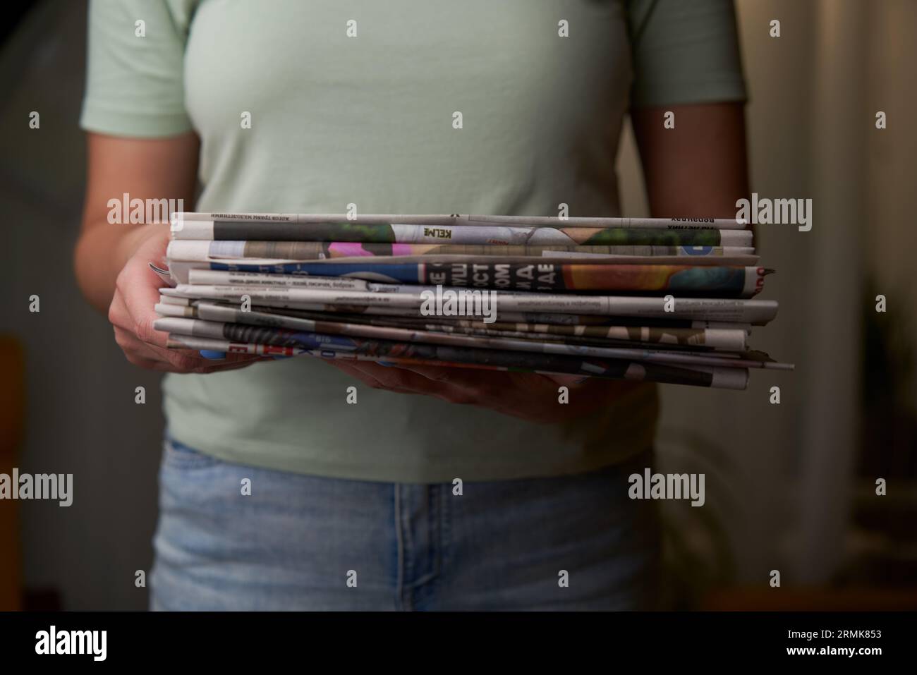 Eine Frau stapelt alte Zeitungen in einem Stapel, Altpapier sammelt. Vorbereitung von Papierabfällen für das Recycling. Stockfoto