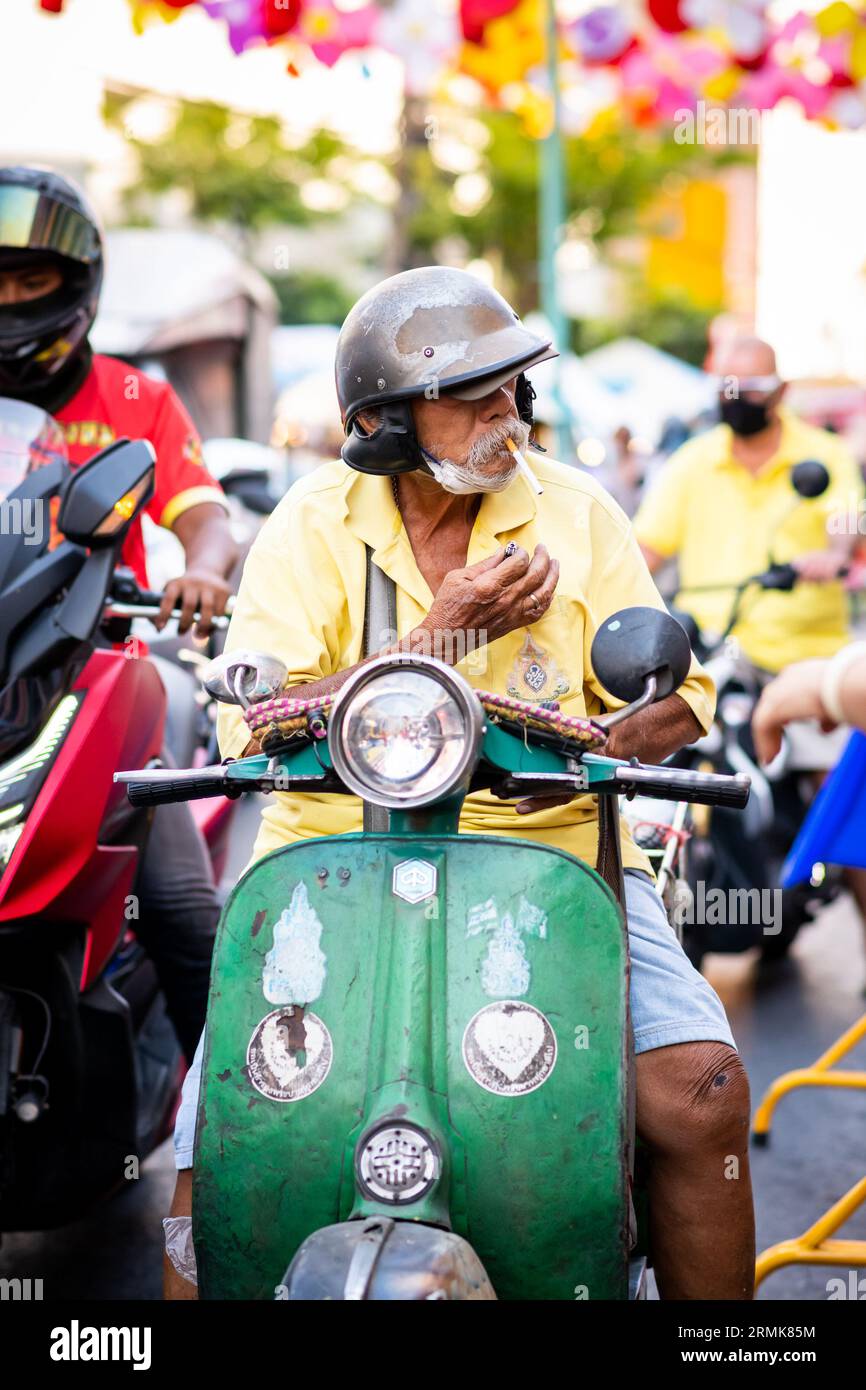 Ein alter Thailänder hält seine klassische grüne vespa auf der Yaowarat Rd. An China Town, Bangkok, Thailand. Stockfoto