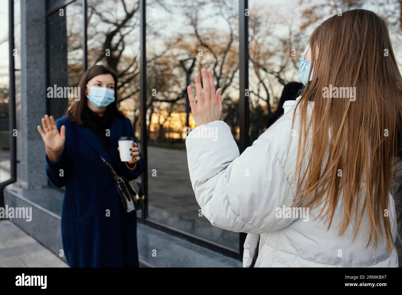 Freundinnen mit Masken winken Stockfoto