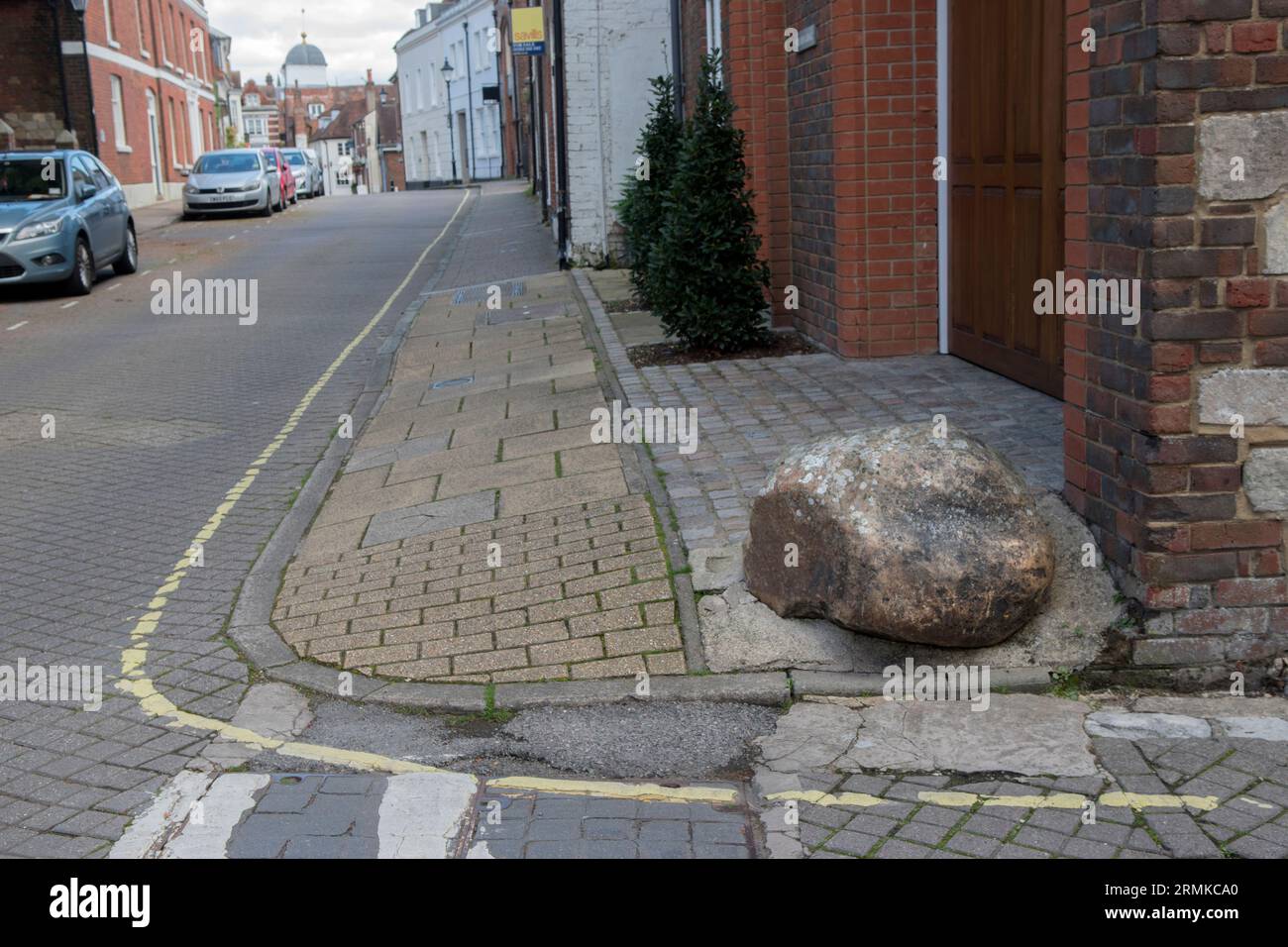 Moot Stone, außerhalb eines modernen Hauses, das auf und um die Basis eines alten Hauses an der Ecke von St Thomas Street und Minster Lane gebaut wurde. Bild entlang der St. Thomas Street. Winchester, Hampshire, England 2023. Stockfoto