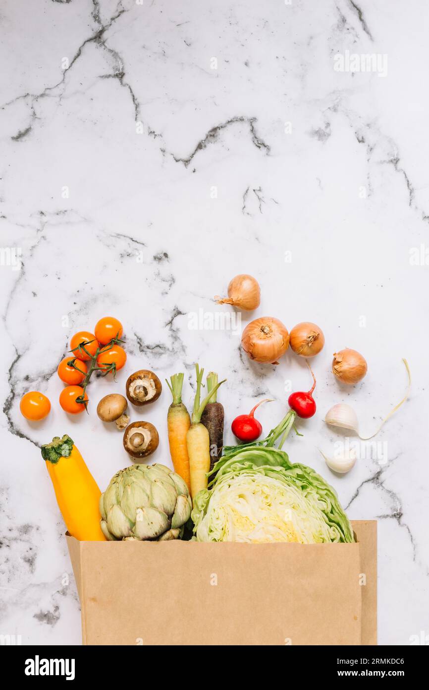 Gemüse verschüttet aus braunen Papiertüte Marmor Hintergrund Stockfoto