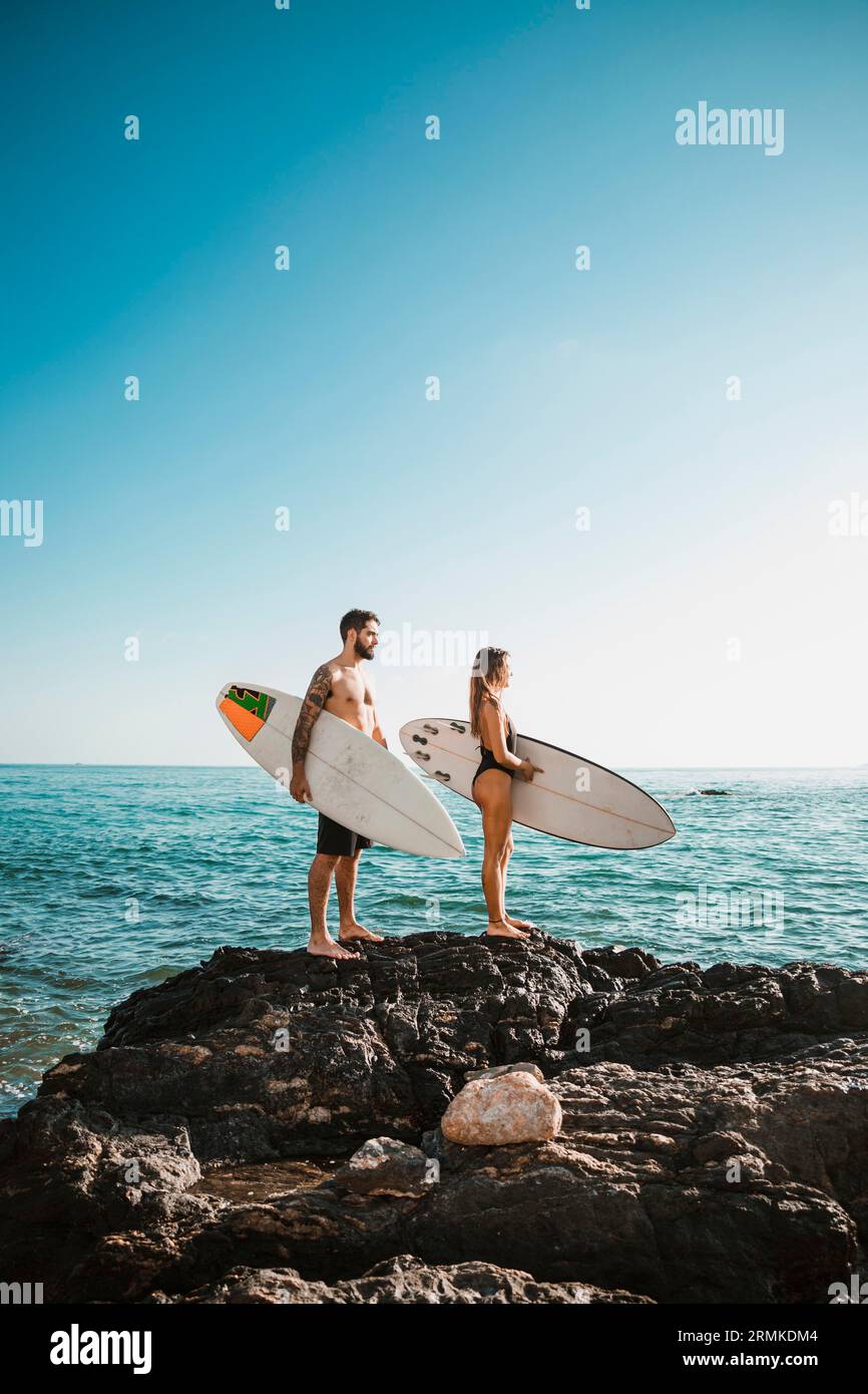 Junge Frau mit Surfbrettern Stein in der Nähe des Meeres Stockfoto