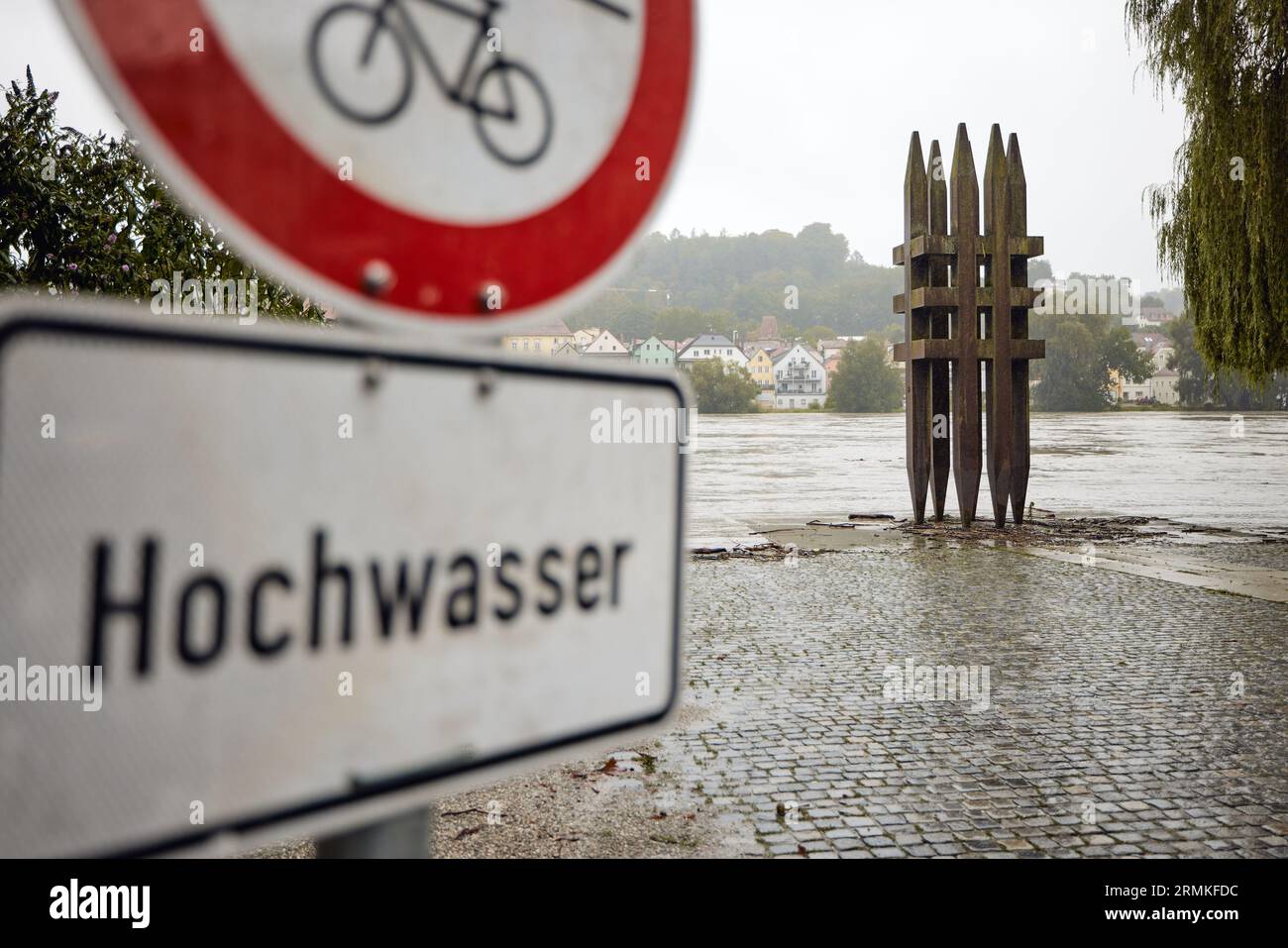 Passau, Deutschland. 29. August 2023. Ein Schild mit der Aufschrift „Flood“ steht auf dem „Platz der Opfer des Nationalsozialismus“, wo der Gasthof seine Ufer überflutete und gegen 9:00 Uhr die Gedenkstätte mit einer Höhe von 5,90 Metern erreichte. Die für die Donau in der Nacht prognostizierte Stufe 4 (8,50 Meter) wurde nicht erreicht. Sie hatte den Gipfel mit acht Metern gegen zehn Uhr erreicht und ist seither leicht zurückgegangen. Tobias C. Köhler/dpa/Alamy Live News Stockfoto