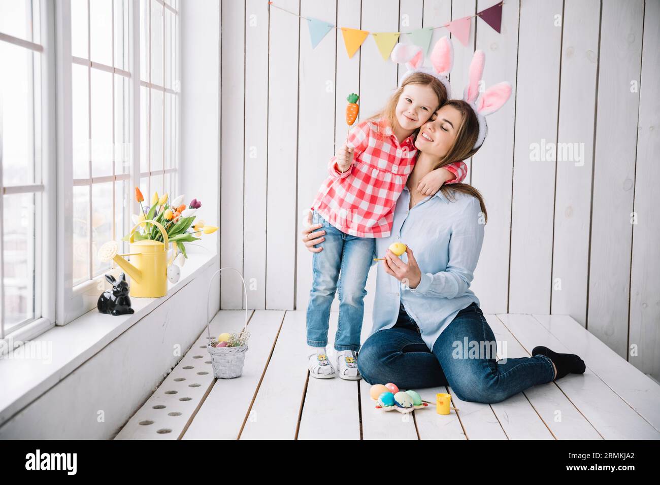 Kleines Mädchen Mutter Häschen Ohren sitzen mit ostereiern Stockfoto