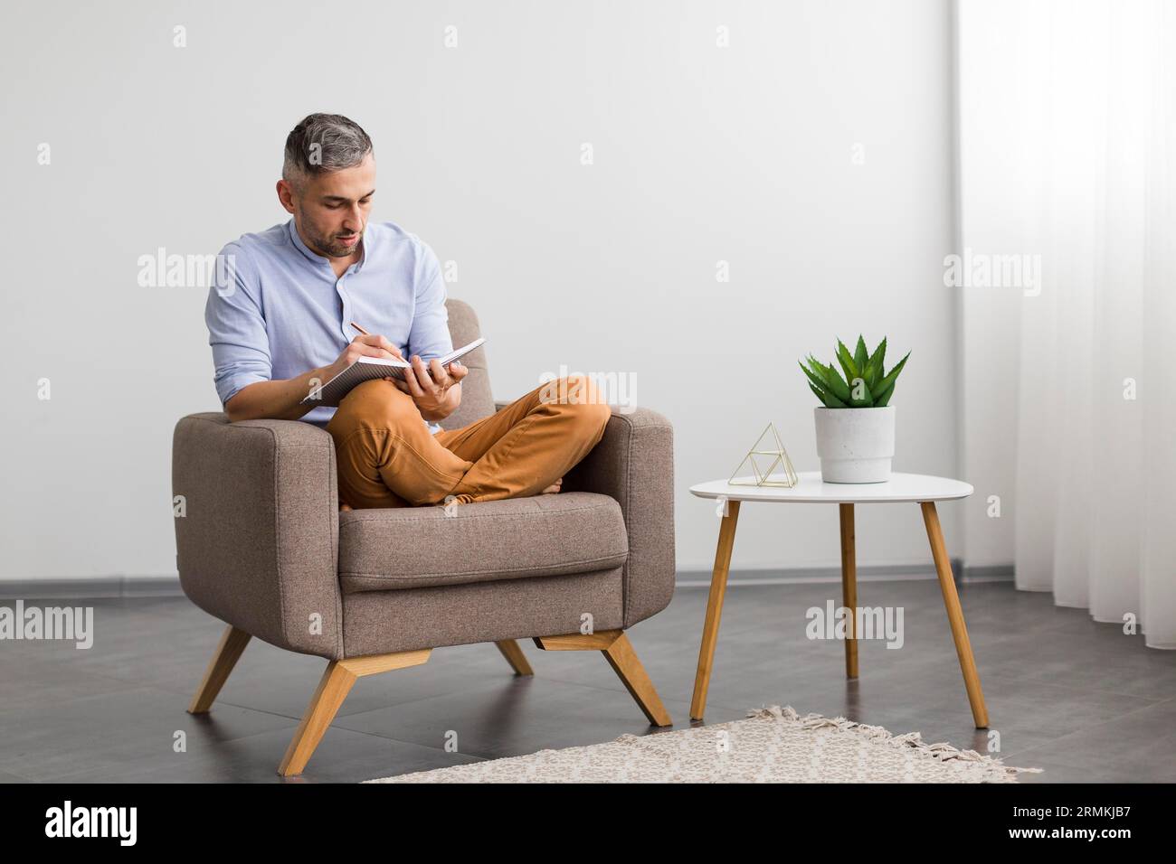 Mann sitzt auf dem Stuhl und schreibt seine Tagesordnung Stockfoto