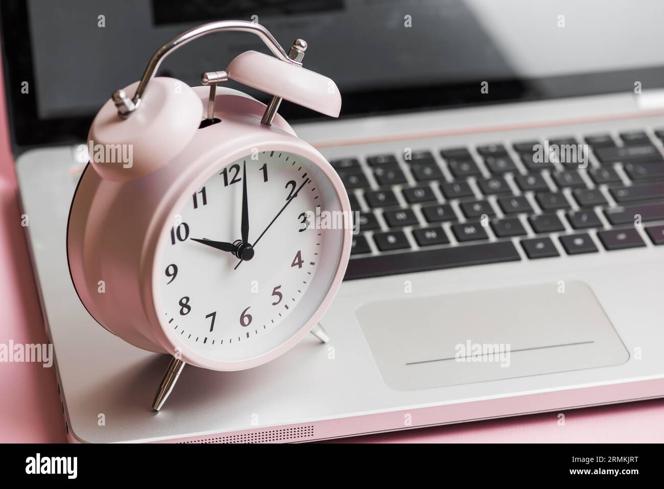 Rosafarbener Vintage-Wecker, Laptop geöffnet Stockfoto