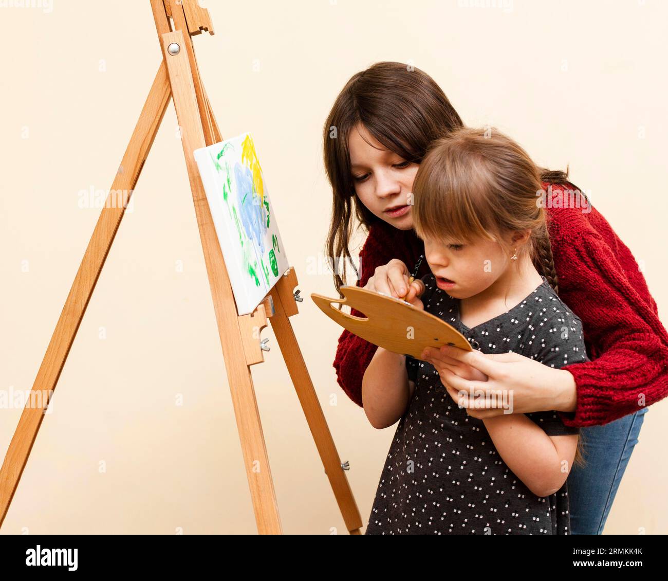 Side View Girl Help Girl with Down syndrome paint Stockfoto