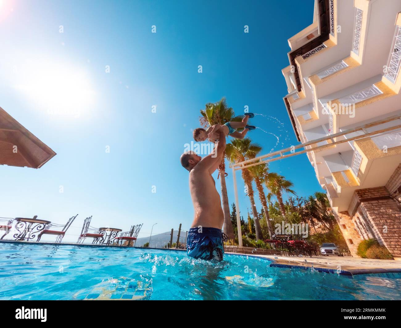 Vater und Sohn sind im Sommer im Pool und spielen, genießen und heben ihn im Urlaub auf Stockfoto