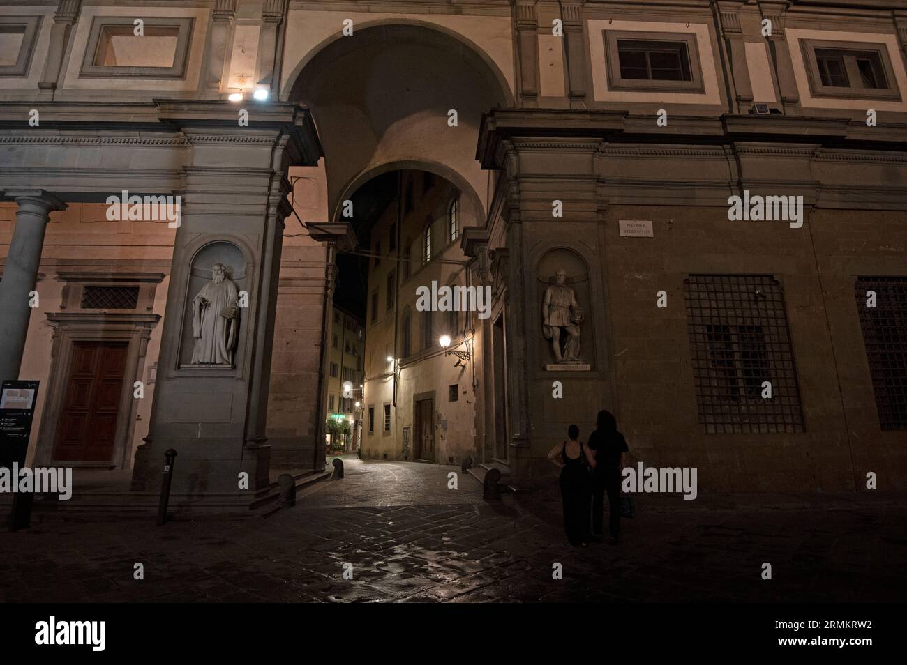 Nach Einbruch der Dunkelheit, als der Regen aufhörte, gibt es einen hohen Fußgängerbogen mit zwei Wandstatuen einiger berühmter italienischer Künstler im Stockfoto