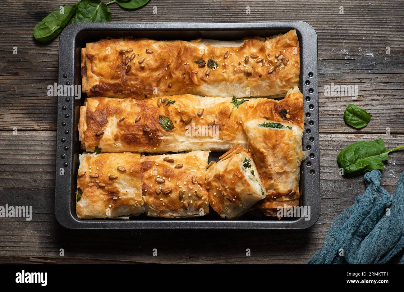 Frisch gebackener hausgemachter gerollter Kuchen mit Spinat in einem Backblech auf einem hölzernen Hintergrund. Draufsicht. Stockfoto