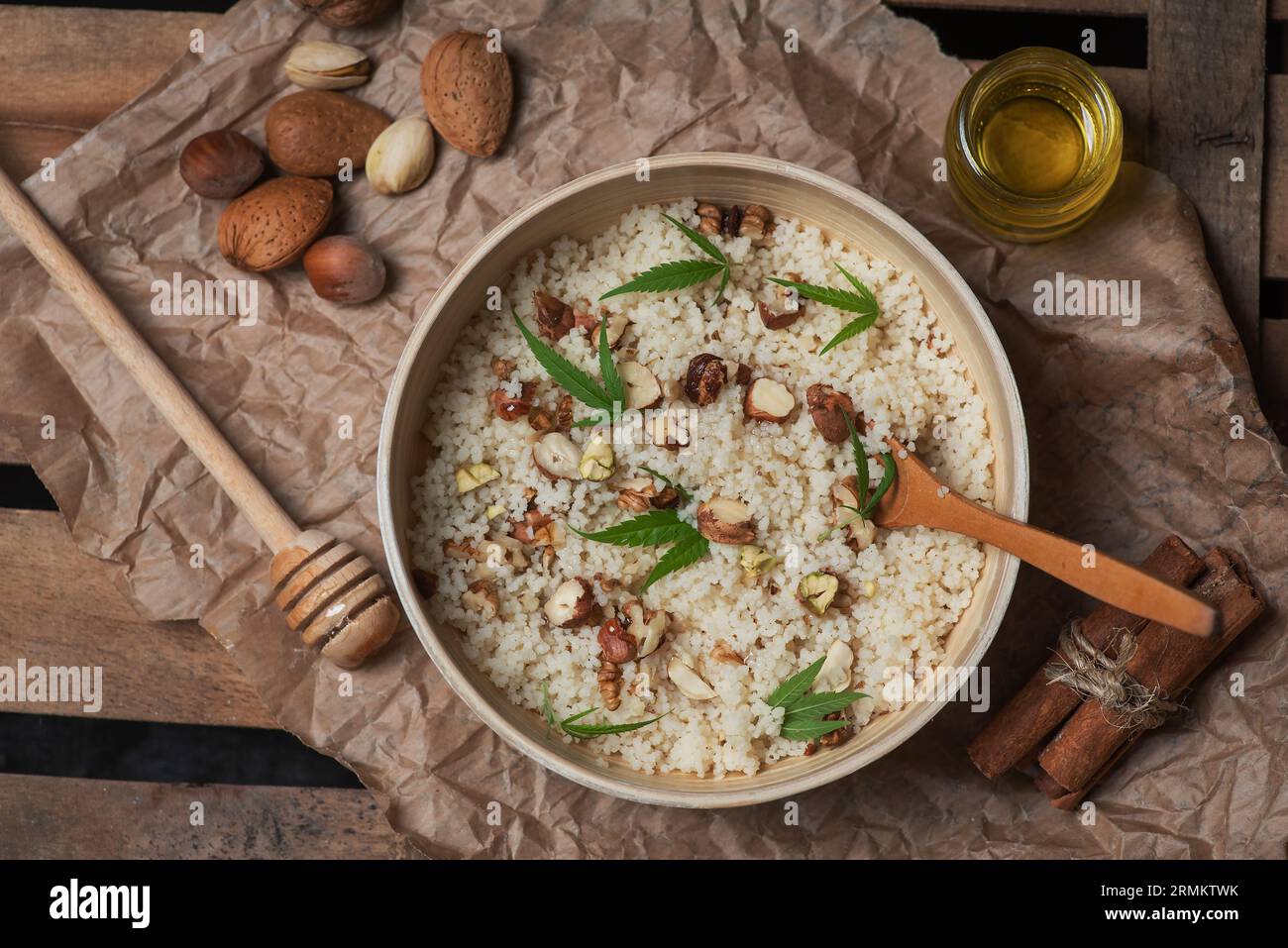Couscous mit Nüssen, Marihuanablättern und Cannabisöl in einer Schüssel auf einem hölzernen Hintergrund Stockfoto