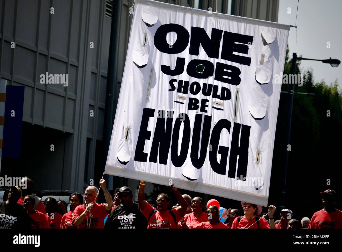Die Teilnehmer tragen ein großes Schild mit der Aufschrift One Job Should Be Enough, während der jährlichen Labor Day Parade entlang der Delaware Avenue in Philadelphia, PA. Stockfoto