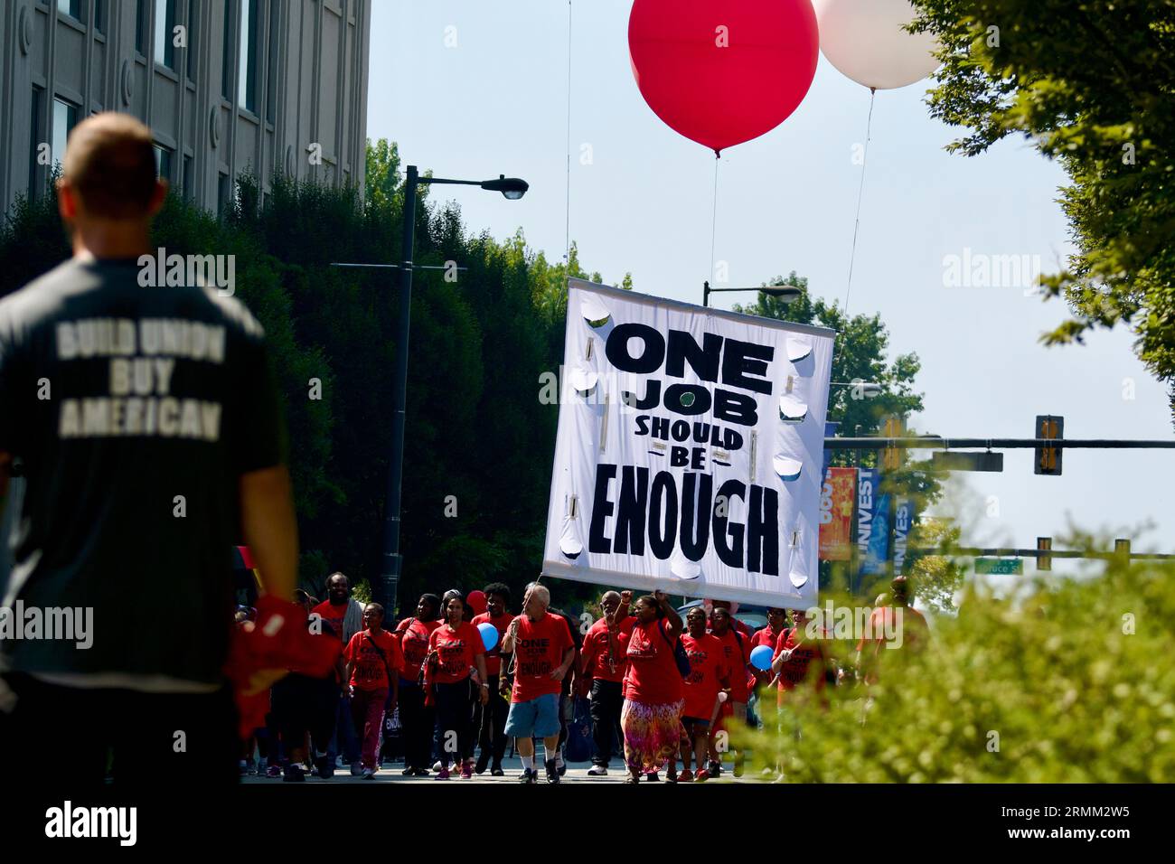 Die Teilnehmer tragen ein großes Schild mit der Aufschrift One Job Should Be Enough, während der jährlichen Labor Day Parade entlang der Delaware Avenue in Philadelphia, PA. Stockfoto