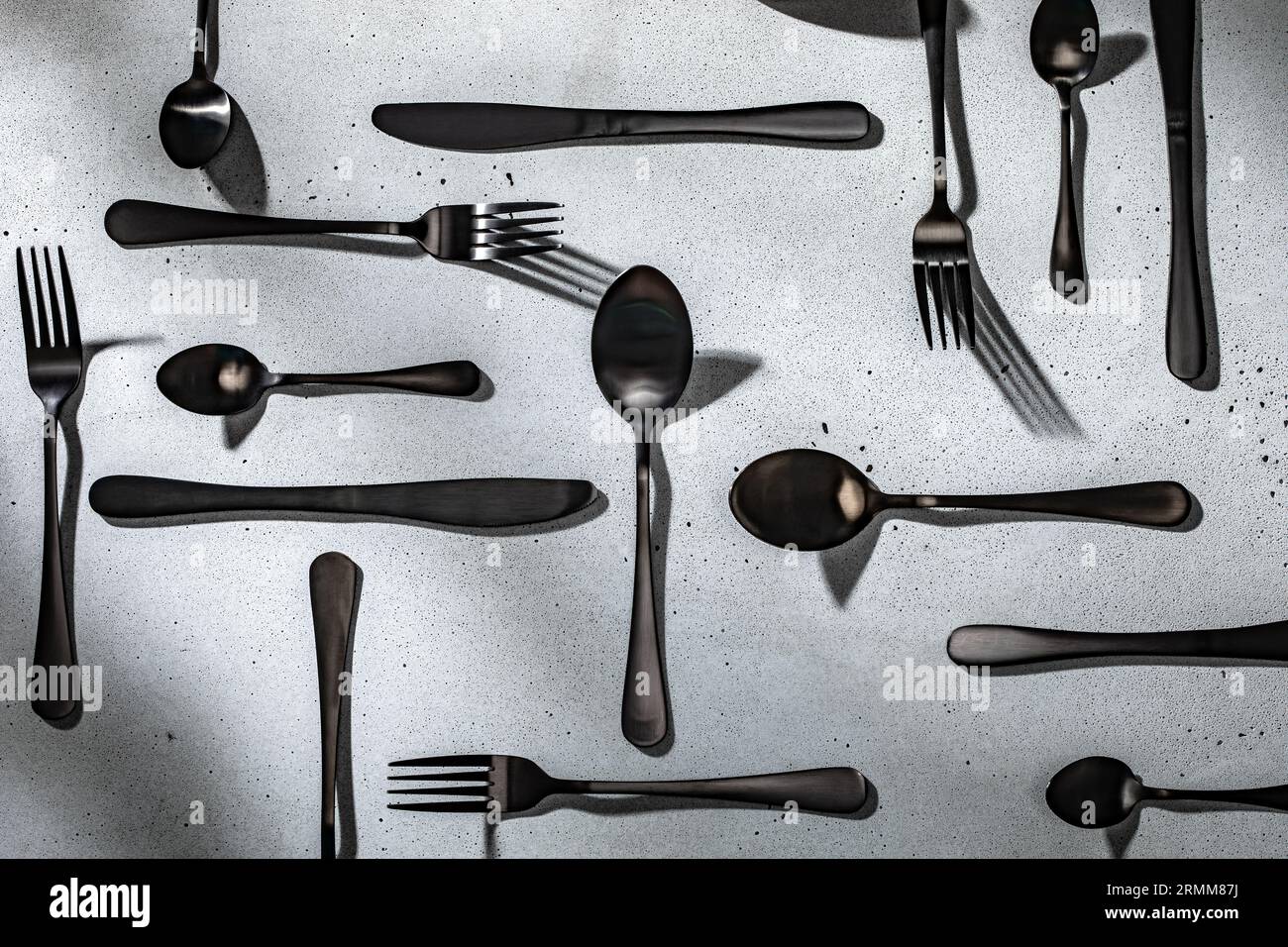 Schwarzes Besteck auf neutralgrauem Betonhintergrund Stockfoto