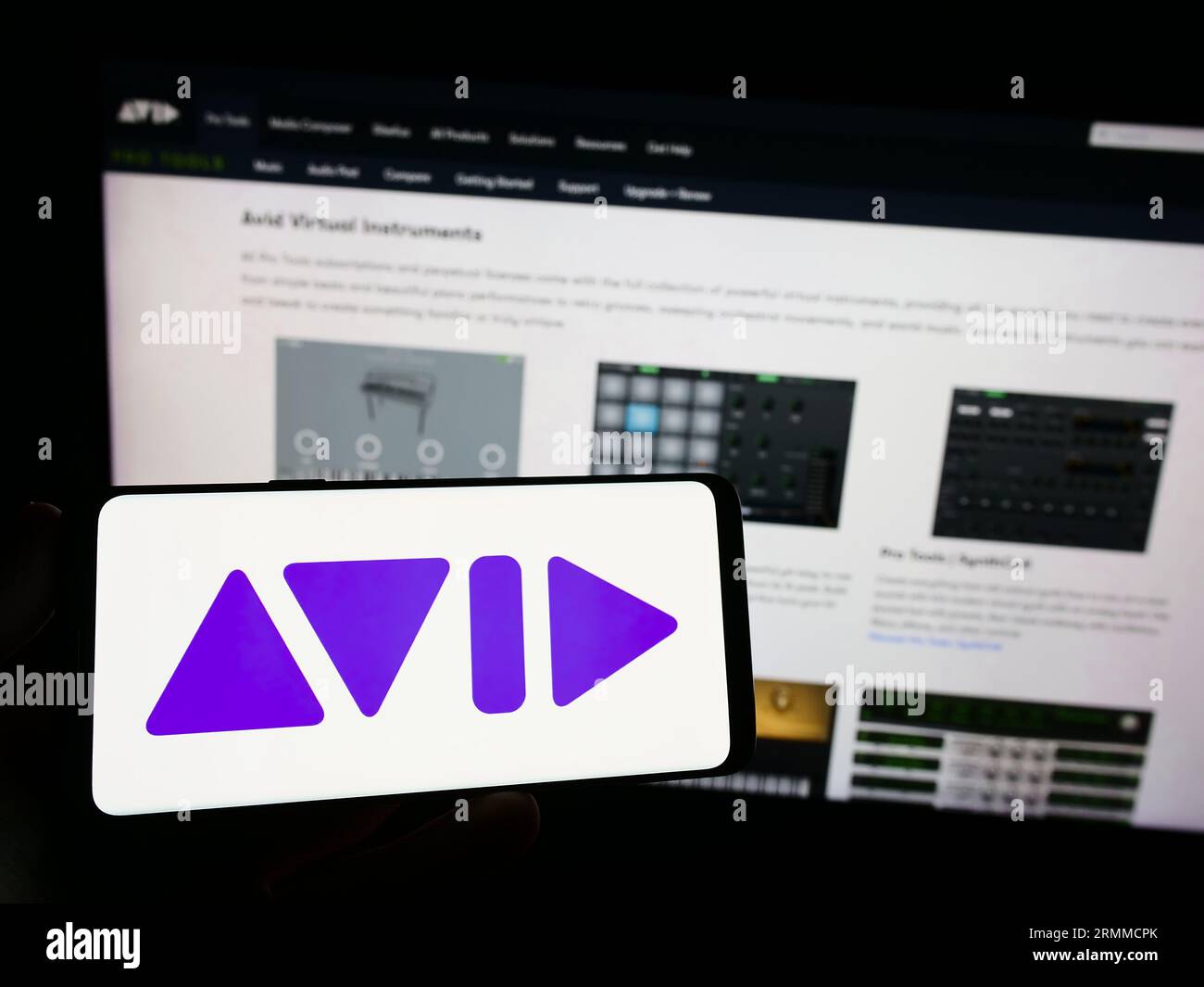 Person, die ein Mobiltelefon mit dem Logo des amerikanischen Softwareunternehmens Avid Technology Inc. Auf dem Bildschirm vor der Webseite hält. Konzentrieren Sie sich auf das Display des Telefons. Stockfoto