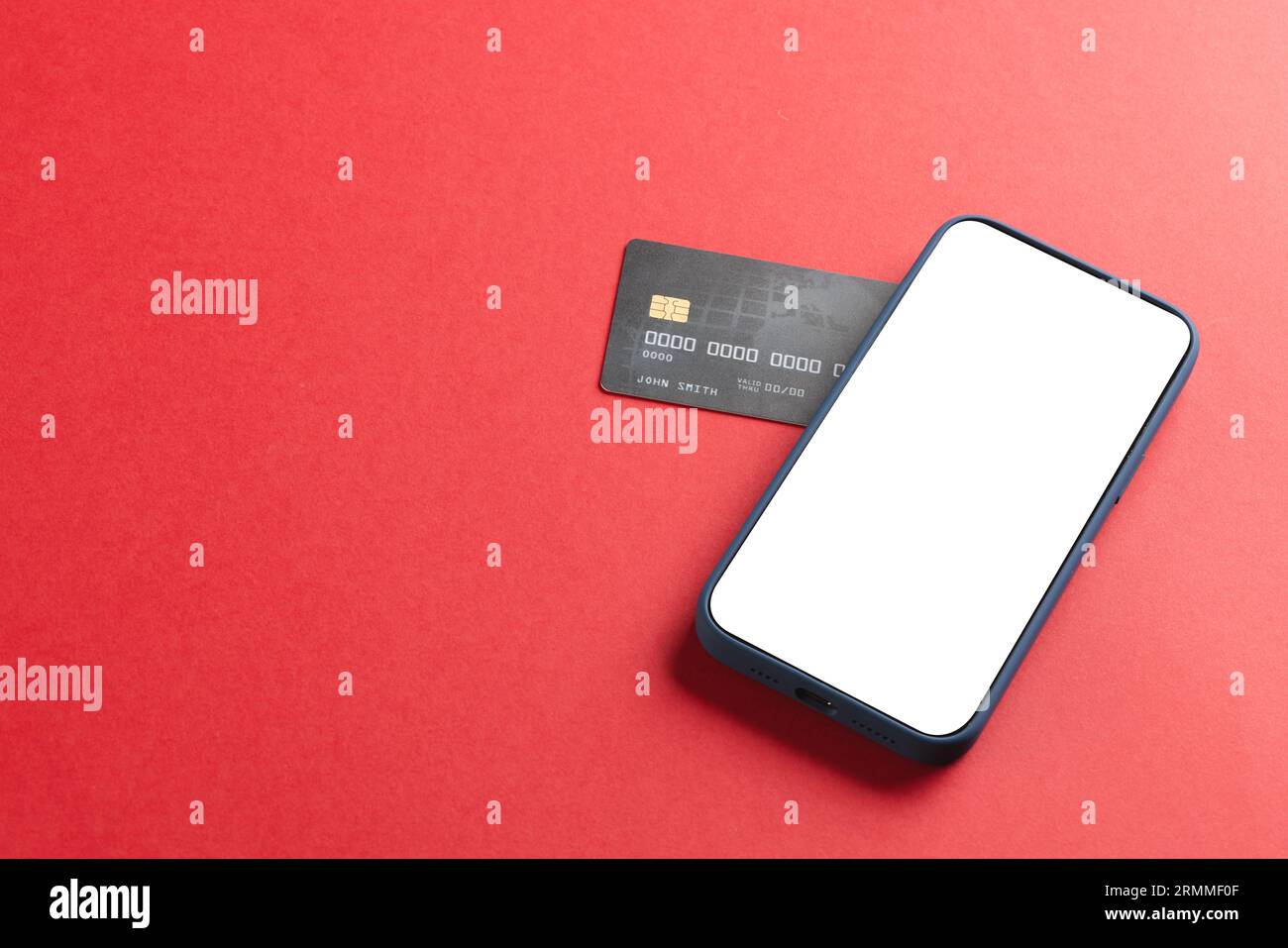 Smartphone mit leerem Bildschirm und Kreditkarte auf rotem Hintergrund Stockfoto