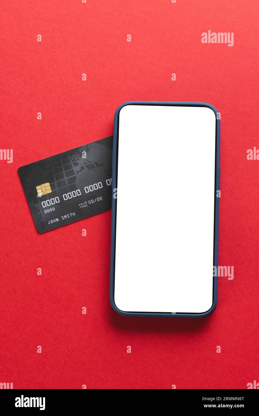 Vertikales Bild des Smartphones mit leerem Bildschirm und Kreditkarte auf rotem Hintergrund Stockfoto