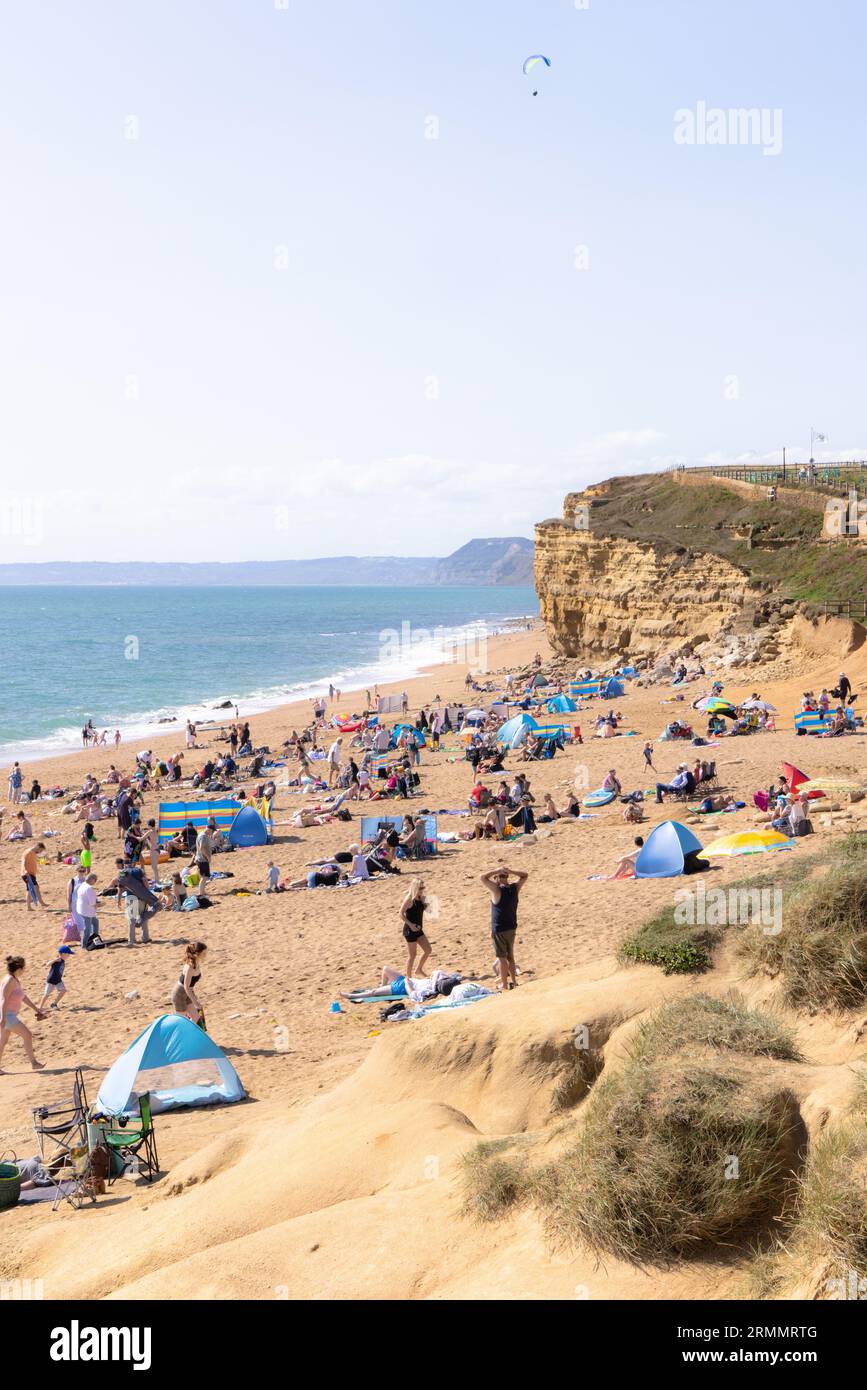 Südküste UK Strand Sommersonne - Leute, die im August am Hive Beach, Dorset UK, ein Teil der Jurassic Coast, sonnen Stockfoto