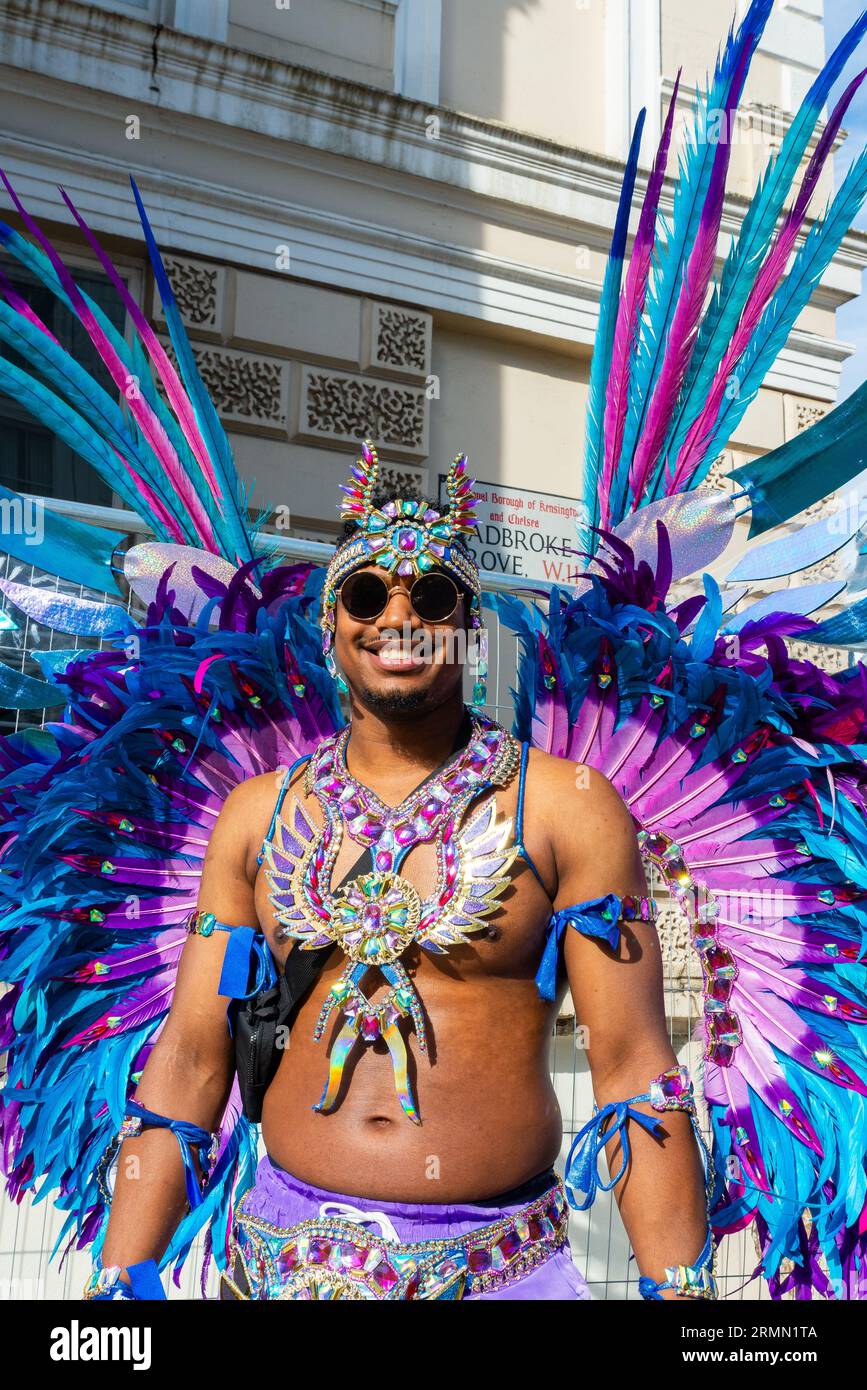 Männlicher Teilnehmer an der Notting Hill Carnival Grand Parade 2023, London, UK. Farbenprächtiges Kostüm mit bunten Federn Stockfoto