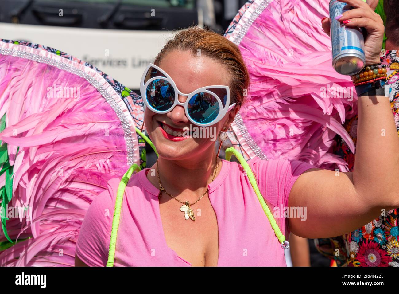 Teilnehmerin bei der Notting Hill Carnival Grand Parade 2023 in London. Weißes Weibchen mit rosa Flügeln aus Federn Stockfoto