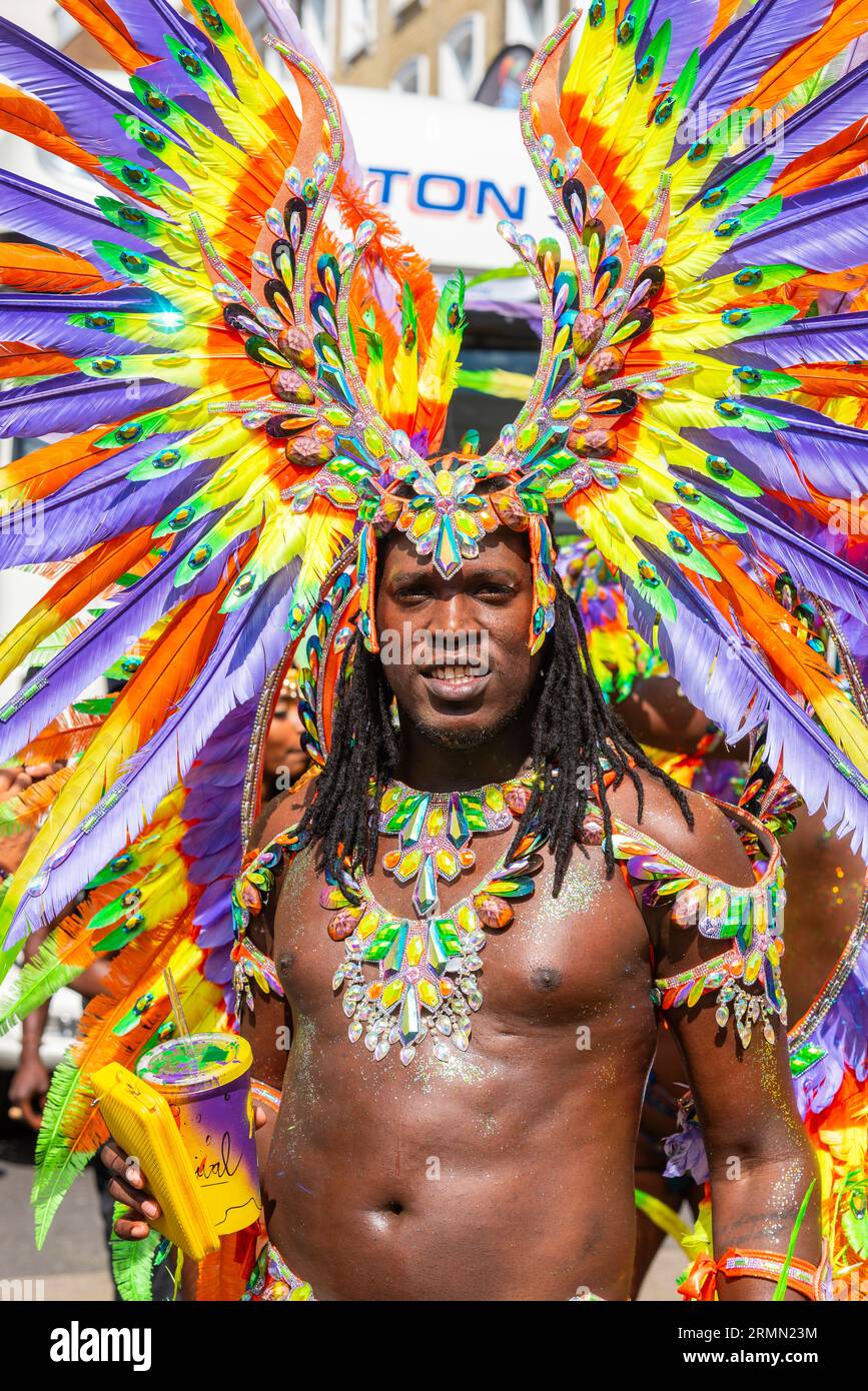 Männlicher Teilnehmer an der Notting Hill Carnival Grand Parade 2023, London, UK. Farbenfrohes Kostüm mit Federkleid und Glitzersteinchen Stockfoto