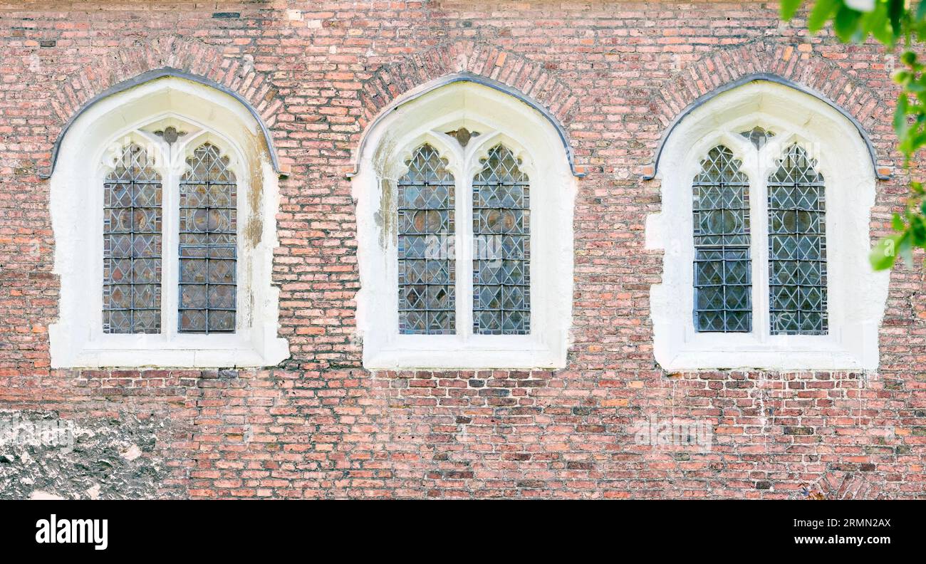 Drei bogenförmige Fenster auf einer roten Backsteinmauer am Queens' College, University of Cambridge, England. Stockfoto