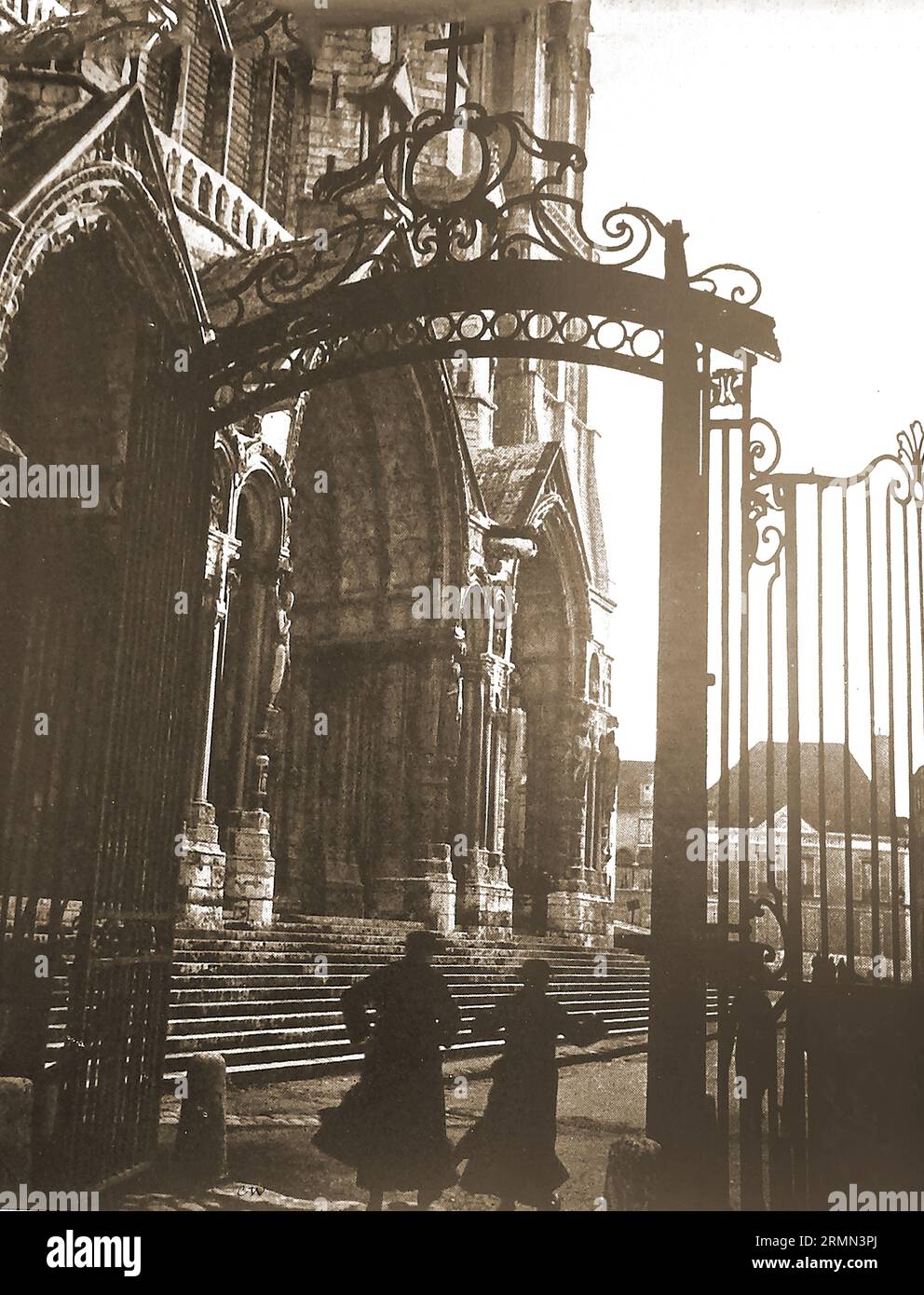 Frankreich - 1939 - Eingang zur Kathedrale von Chartres mit zwei Priestern unter gusseisernem Tor - Frankreich - 1939 - Entrée de la cathédrale de Chartres avec deux prêtres sous une porte voûtée en fonte Stockfoto